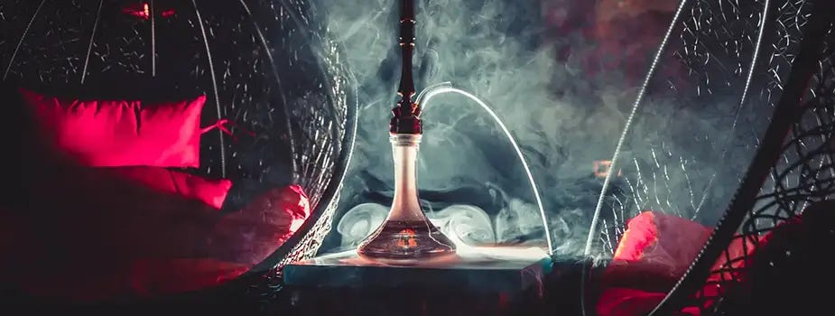 Image of hookah on table with smoke behind with mood lighting and two decorative hanging chairs