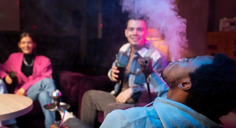 People gathered around a hookah and exhaling clouds of smoke