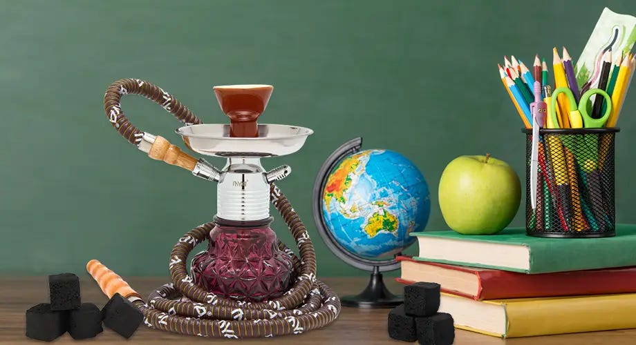 Desk with chalkboard behind it with a MYA Minionette hookah and books and pencils