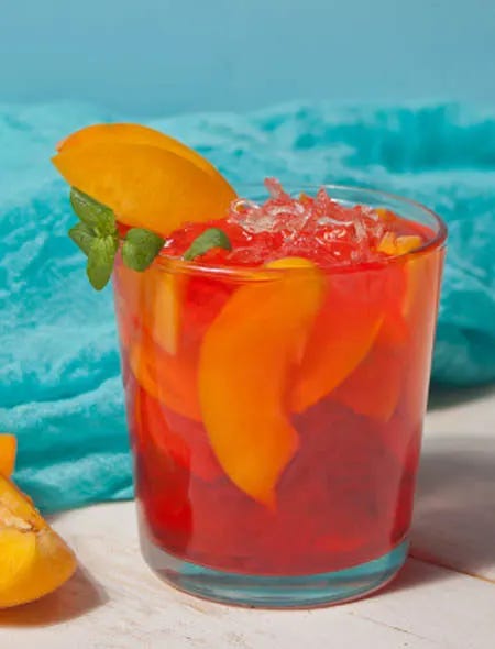 Glass of iced peach tea with pieces of peach