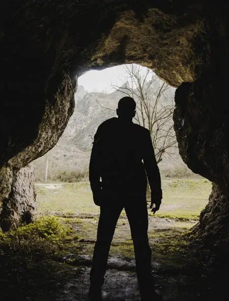 Silhouette of a man looking out from a cave