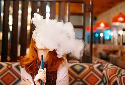 Lady blowing hookah smoke in lounge