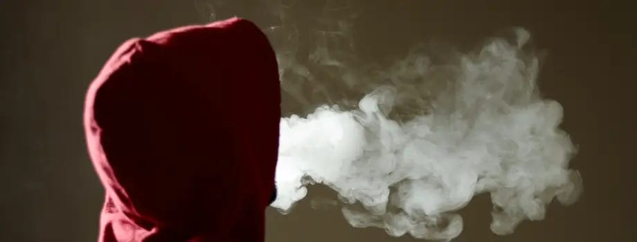 Person smoking vape device blowing smoke