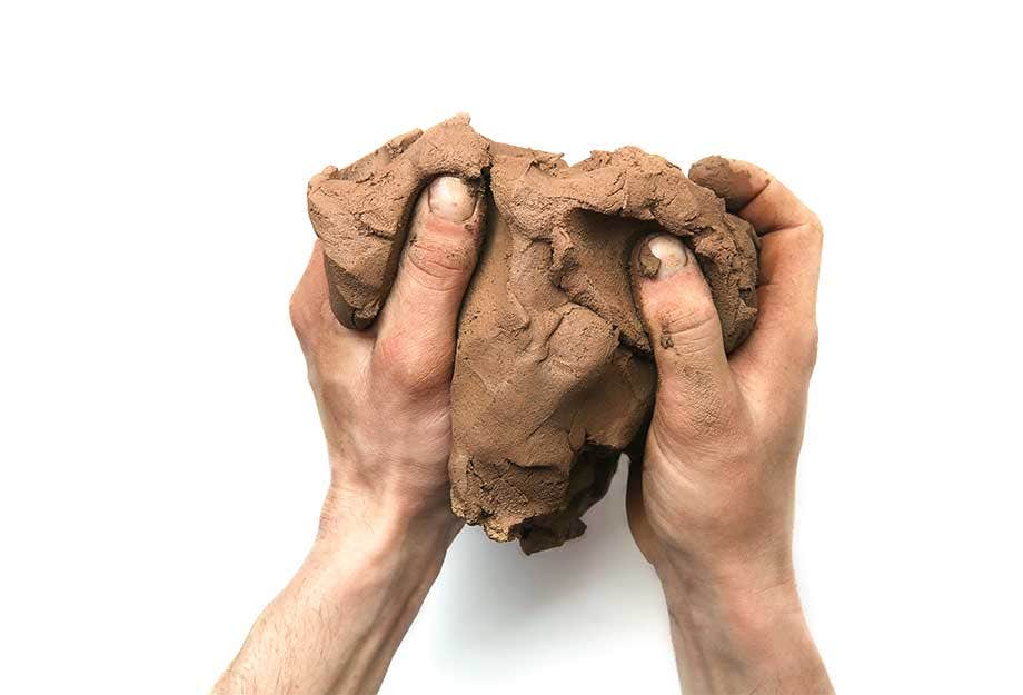 A person handling a lump of raw clay material